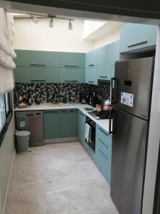a kitchen with blue cabinets and a stainless steel refrigerator at Aqua Royal Alexus Luxury Holiday Apartments Girne in Kérynia