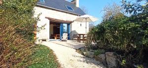 a white cottage with an umbrella and a table at La Ferme du Père in Kermorocʼh