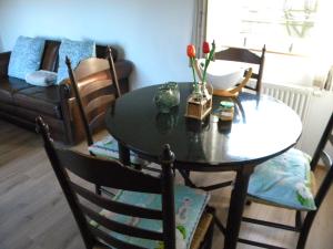 a dining room table and chairs with a table and a couch at Bungalow De Perenboom in Westkapelle