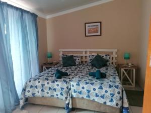een slaapkamer met een bed met blauwe en groene kussens bij WHY NOT GUESTHOUSE in Bothaville