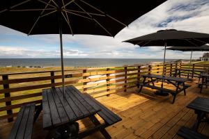 a wooden deck with benches and umbrellas on the beach at GOLF View Hotel & Macintosh Restaurant in Lossiemouth