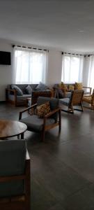 a living room with couches and tables and windows at Hôtel Marbella in Lomé