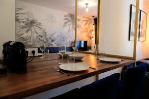 a wooden table with plates and wine glasses on it at Studio l'évasion, parfait pour vous détendre in Divonne-les-Bains