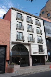 a white building with balconies on a street at Hoteles Bogotá Inn Santa Bárbara Usaquén in Bogotá