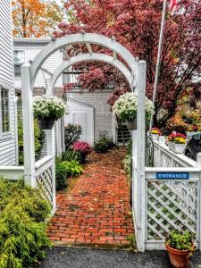 a white gate with a brick walkway with flowers at Clark Currier Inn in Newburyport