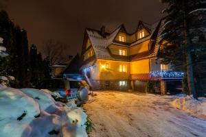 a large house with a snow covered yard at night at Willa u Zofii in Zakopane