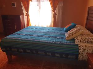 a bed with two pillows on it with a window at Hostal Candelaria in San Pedro de Atacama