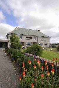 ein Haus mit einem Blumengarten davor in der Unterkunft Sandwick Bay Guest House in Stornoway