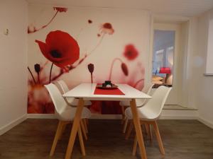 una mesa y sillas con un mural de amapola roja en la pared en Ferienwohnung Rheinblick Koblenz, en Coblenza