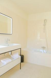 La salle de bains blanche est pourvue d'un lavabo et d'une baignoire. dans l'établissement Hôtel IMPERATOR Béziers, à Béziers