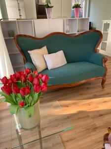 a green couch and a vase of red flowers at Am Kittken in Altenberge