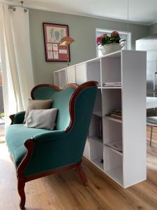 a green chair in a room with a book shelf at Am Kittken in Altenberge