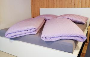 ein Bett mit lila Kissen darüber in der Unterkunft FEWO Rophaienblick in Isenthal