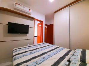 a bedroom with a bed and a tv on the wall at Apartamento Jardim das Palmeiras 2 Ubatuba in Ubatuba +21 photos