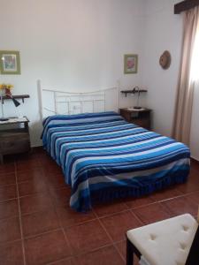 1 dormitorio con 1 cama con manta de rayas azules en Casa Marisa, en Conil de la Frontera