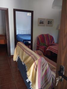 1 dormitorio con espejo, 1 cama y 1 silla en Casa Marisa, en Conil de la Frontera