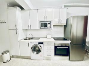 uma cozinha com armários brancos e uma máquina de lavar roupa em EDIFICIO CHAPARIL em Nerja