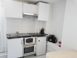a white kitchen with a sink and a microwave at Studio neuf meublé Rosny-sous-Bois in Rosny-sous-Bois