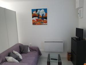 a living room with a purple couch and a painting on the wall at Studio neuf meublé Rosny-sous-Bois in Rosny-sous-Bois
