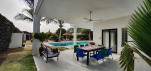 um pátio com uma mesa e cadeiras e uma piscina em La Maison Blanche à Ngaparou, splendide villa contemporaine em Ngaparou