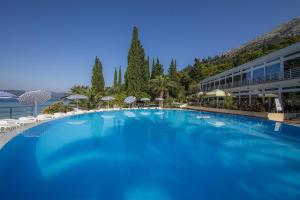 una gran piscina azul con sillas y un edificio en Orsan Hotel by Aminess en Orebić