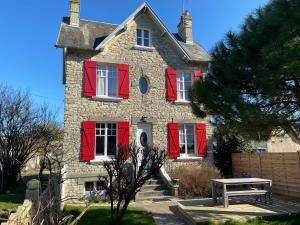 an old stone house with red shutters and a picnic table at Le Martin Pêcheur in Port-en-Bessin-Huppain