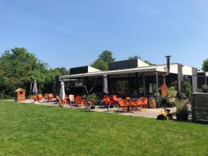 a restaurant with orange chairs and tables and a lawn at Chalet Bergen NH, Schoorl, Schoorldam in Warmenhuizen