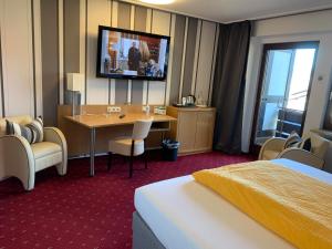 a hotel room with a table and a tv on the wall at Hotel Pension Berghaus Sieben in Bad Laasphe