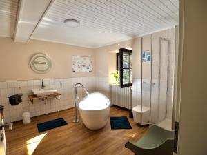 a bathroom with a tub and a toilet and a sink at Scherfsmühle am Mühlbach in Waldrach