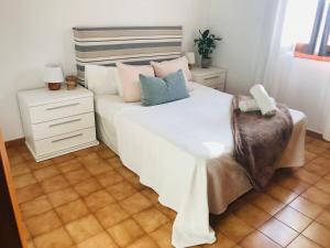 a bedroom with a white bed and a chair at Casa 3 dormitorios Cala Galdana in Cala Galdana