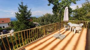 einen Balkon mit einem Tisch und einem Sonnenschirm in der Unterkunft Apartman SABADIN in Njivice