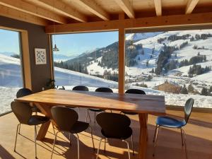 einen Tisch und Stühle in einem Zimmer mit einem großen Fenster in der Unterkunft Alpine Dream Chalet with Spa close to Lake Geneva in Les Mosses