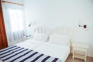 a white bed with a blue and white striped blanket at Mar Azul Playa in Puerto del Carmen