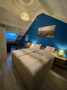 1 dormitorio con 1 cama grande y pared azul en Lise's Place en Vrouwenpolder