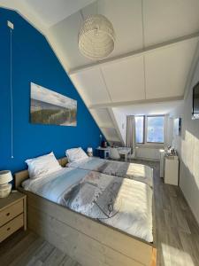a bedroom with blue walls and a large bed at Lise's Place in Vrouwenpolder