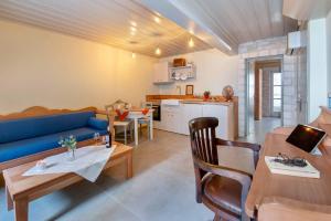 a living room with a blue couch and a kitchen at Lakka Stone House 0 in Gaios