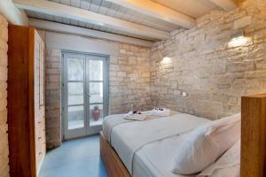 a bedroom with a bed with a stone wall at Lakka Stone House 0 in Gaios