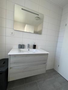 a white bathroom with a sink and a mirror at Lise's Place in Vrouwenpolder