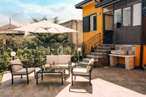 um pátio com uma mesa, cadeiras e um guarda-sol em La Sciara Etna Home em Linguaglossa