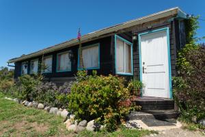 ein schwarzes Haus mit einer weißen Tür und ein paar Blumen in der Unterkunft Cabañas ChiloeisLife Countryside in Castro