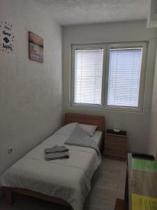 a small bedroom with a bed and two windows at Villa Ivanovi in Ohrid