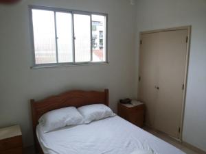 a bedroom with a white bed and a window at Apartamento Cabo Frio in Cabo Frio