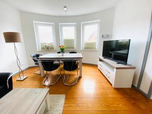 a living room with a table and a flat screen tv at Schöne Ferienwohnung mit großem Garten in Flensburg