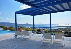 patio z krzesłami i widokiem na wodę w obiekcie White Blue Houses & Apartments Paros w mieście Parikia