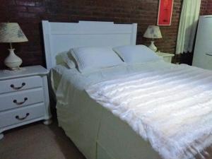 uma cama branca com duas mesas de cabeceira e dois candeeiros em Apartamento no Centro de Gramado em Gramado