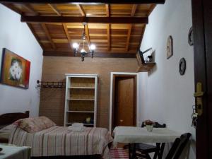 a room with a bed and a table and a chandelier at Chalé das Orquídeas in Monte Verde
