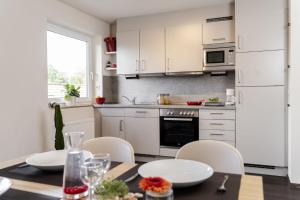 a kitchen with white cabinets and a table and chairs at Hotel & Apartments Böhm in Gravenwerth