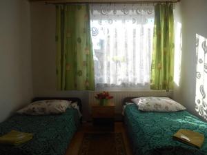 a bedroom with two beds and a window with curtains at Hotelik Gościnny in Radzyń Podlaski