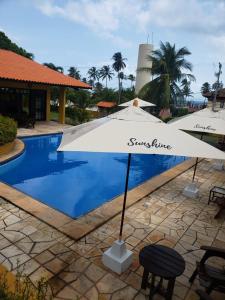 um guarda-chuva branco sentado ao lado de uma piscina em Sunshine Cumbuco em Cumbuco