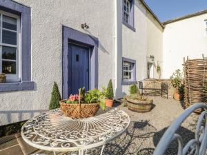 a patio with a table with flowers and a blue door at Beckside Cottage in Welton